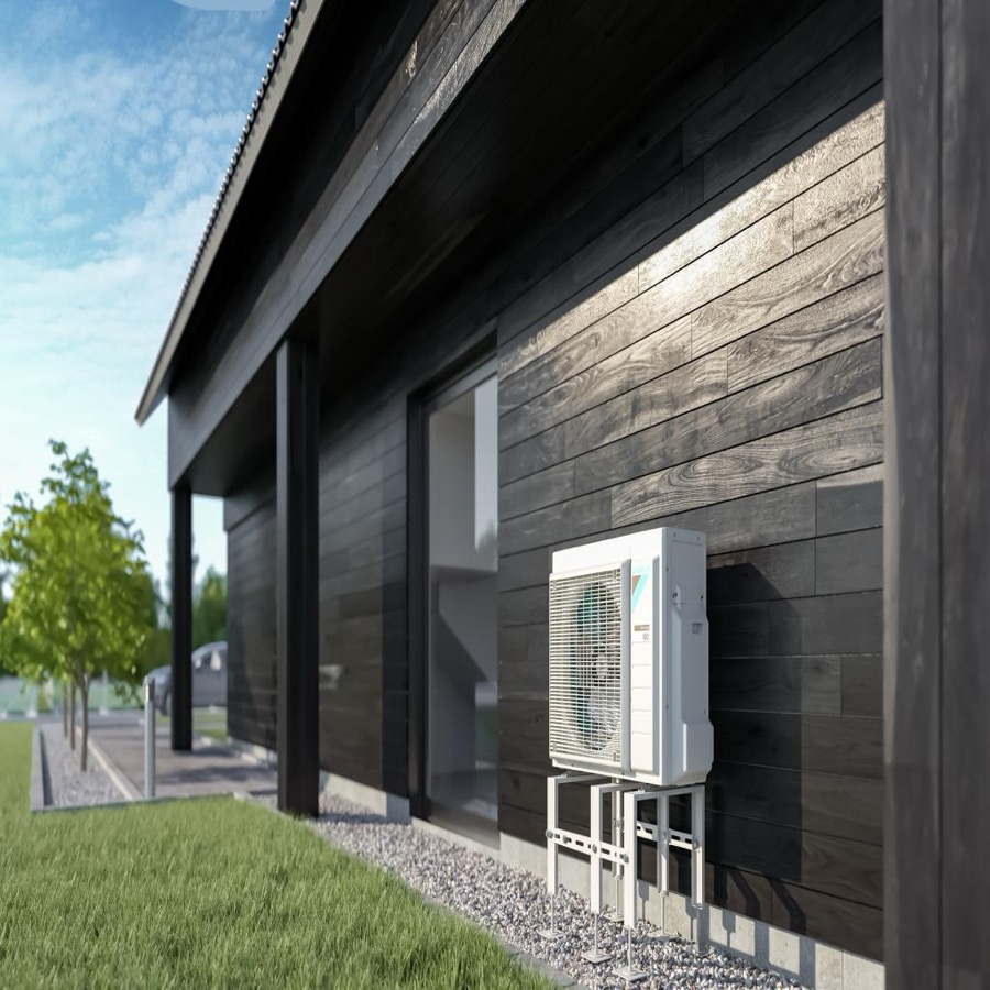 Buitenunit van een Daikin-warmtepomp tegen de houten gevel van een moderne woning